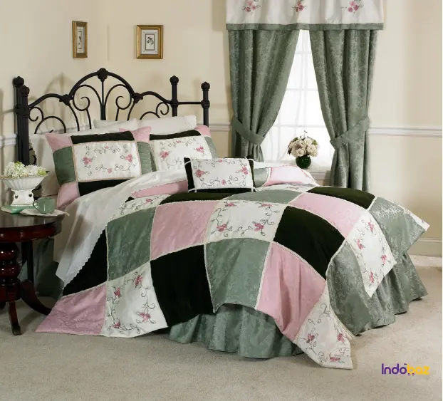 A bedroom layered with embroidered throws, velvet cushions, and a cotton quilt with traditional block prints